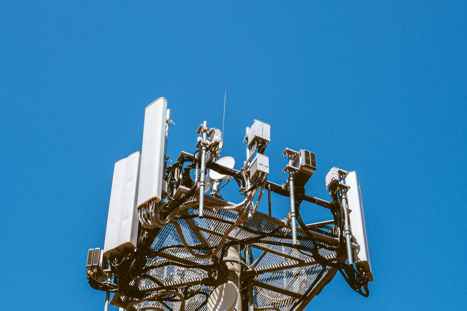 The antenna head of a mobile tower against a clear blue sky